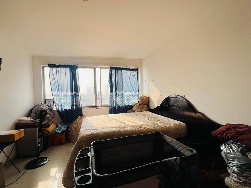 A bedroom featuring tiled flooring and a large sliding window, currently requiring cosmetic updates to the wall finishes.