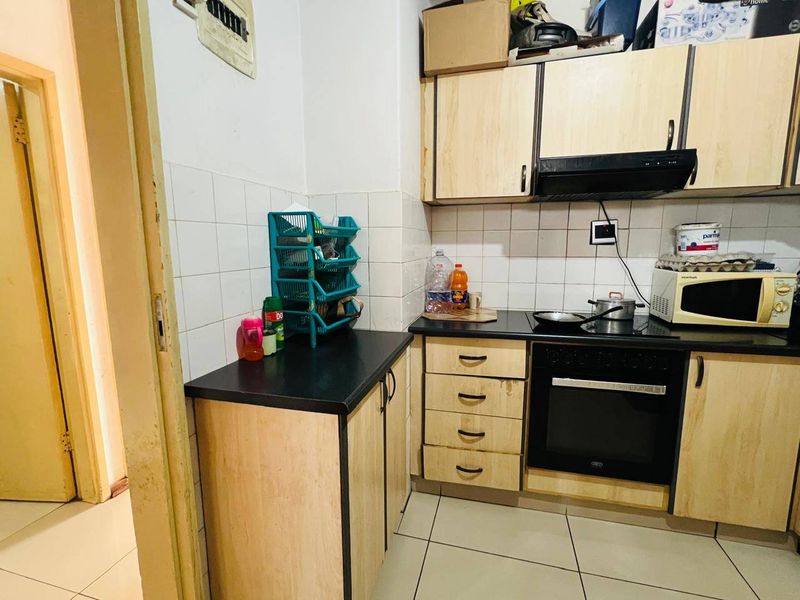 A compact kitchen featuring built-in cabinetry, a tiled backsplash, and integrated oven with extractor fan, requiring cosmetic updates to modernize the space.