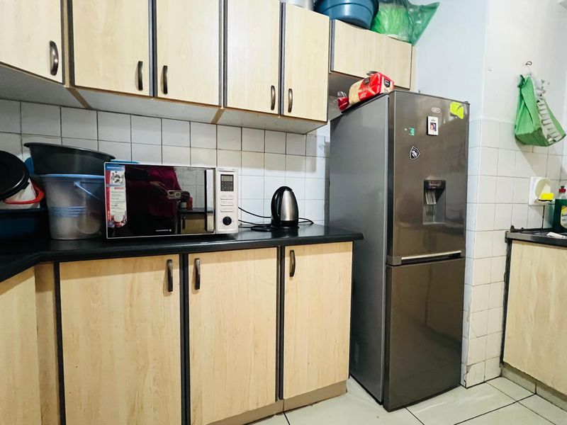 A functional kitchen featuring light wood-look laminate cabinetry, a tiled backsplash, and dark countertops, providing a practical workspace for daily meal preparation.