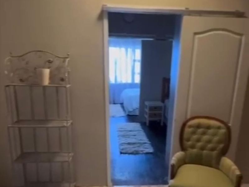 Interior view showing a transition space leading into a bedroom with tiled flooring and a doorway.