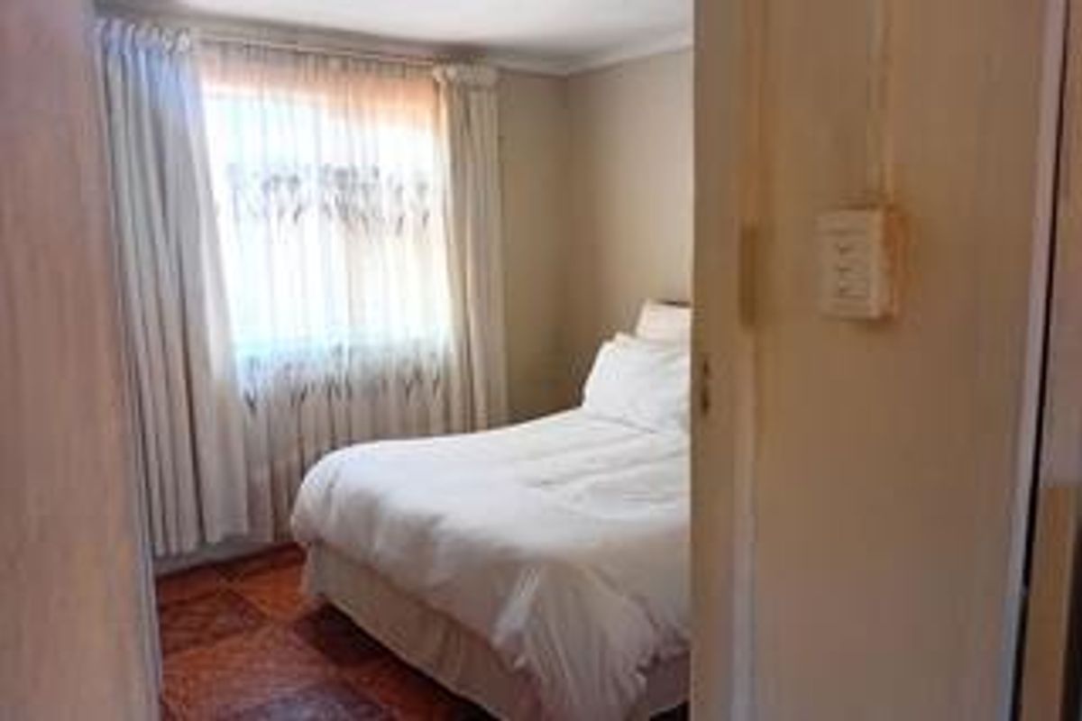 A standard bedroom featuring tiled flooring and window treatments, offering a functional space with neutral wall finishes.