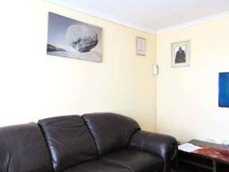 A living room area featuring neutral wall finishes and coving, providing a functional space for relaxation.