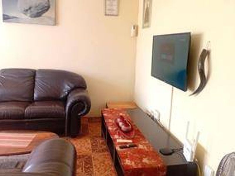A living room area featuring a wall-mounted television and tiled flooring.