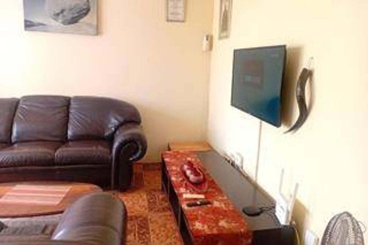 A living room area featuring a wall-mounted television and tiled flooring.