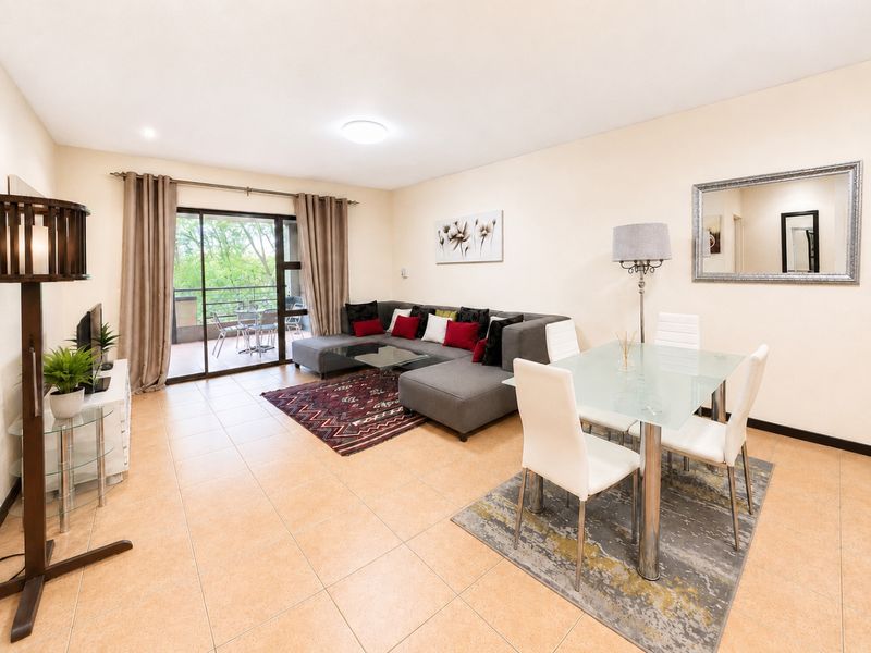 Open-plan living and dining area featuring ceramic floor tiles and a sliding glass door leading to an outdoor balcony.