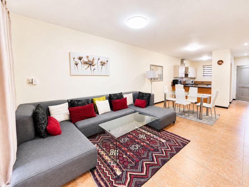 Open-plan living and dining area featuring tiled flooring and a functional kitchen with built-in cabinetry and an extractor fan.
