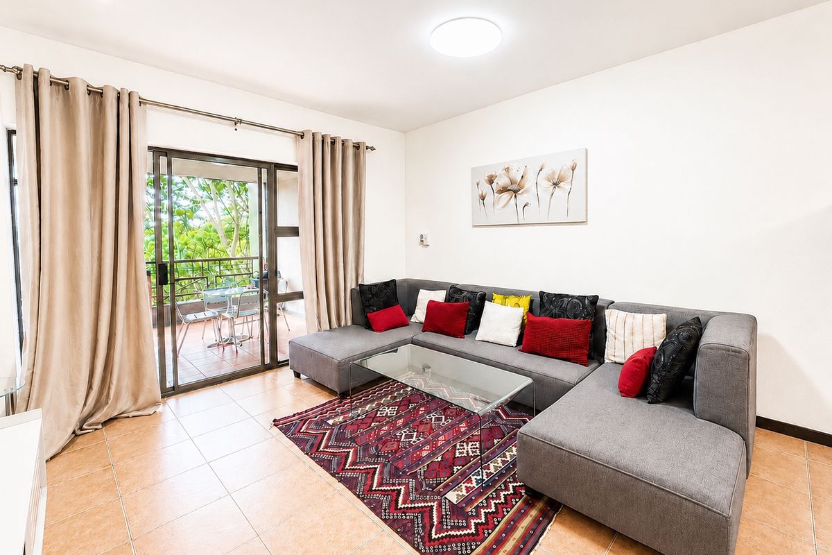 A bright living room featuring tiled flooring and a large sliding glass door providing access to an outdoor balcony area.