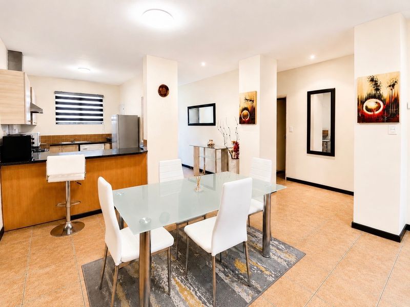 Open-plan living and dining area featuring a functional kitchen with built-in cabinetry, granite countertops, and tiled flooring throughout.