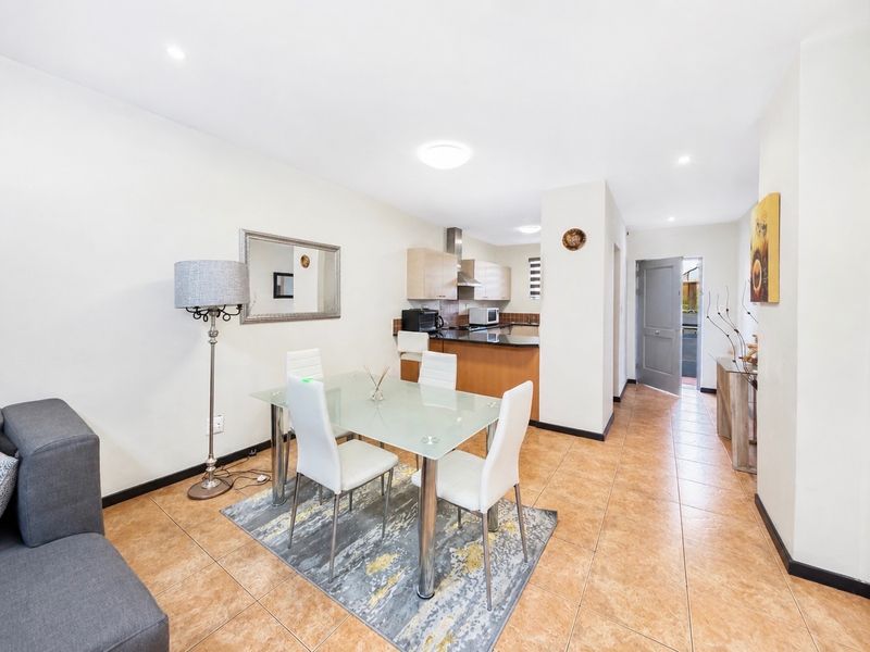 Open-plan living and dining area featuring tiled flooring, recessed lighting, and a functional kitchen with built-in cabinetry and granite countertops.