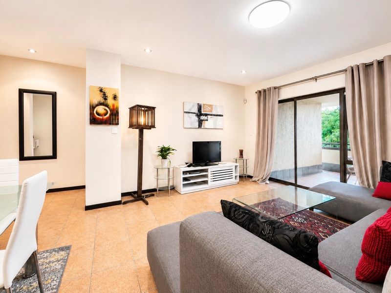 An open-plan living and dining area featuring tiled flooring, recessed lighting, and a large sliding glass door providing access to the balcony.