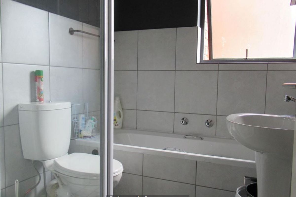 A functional bathroom featuring a bathtub, pedestal basin, toilet, and a separate shower enclosure with tiled walls.