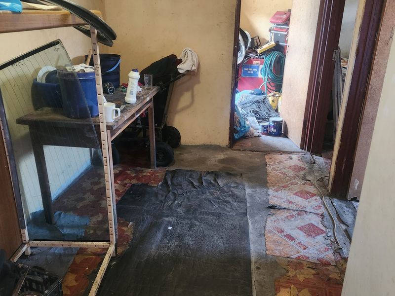 A utility or storage area featuring worn flooring and basic wall finishes, requiring significant maintenance or renovation to improve its functional state.