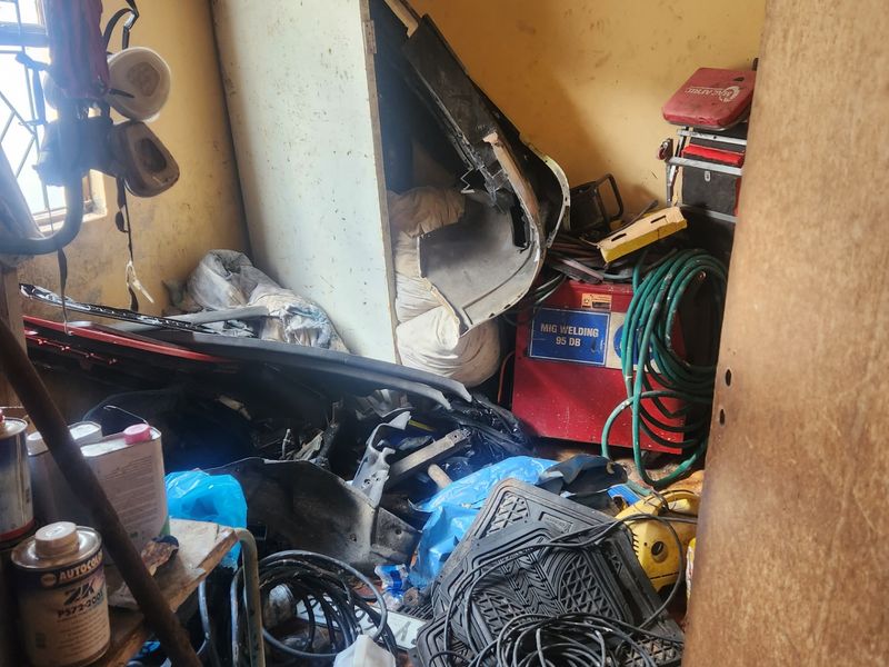 A cluttered utility space or storage room showing significant wear and tear on the walls and flooring.