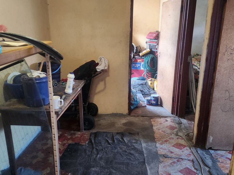 A utility or storage area showing significant wear to the flooring and wall finishes, requiring maintenance and refurbishment to improve the space.