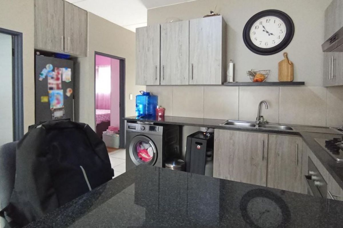 Functional kitchen featuring wood-look cabinetry, granite countertops, a gas hob, and integrated appliances, providing a practical workspace for daily cooking.