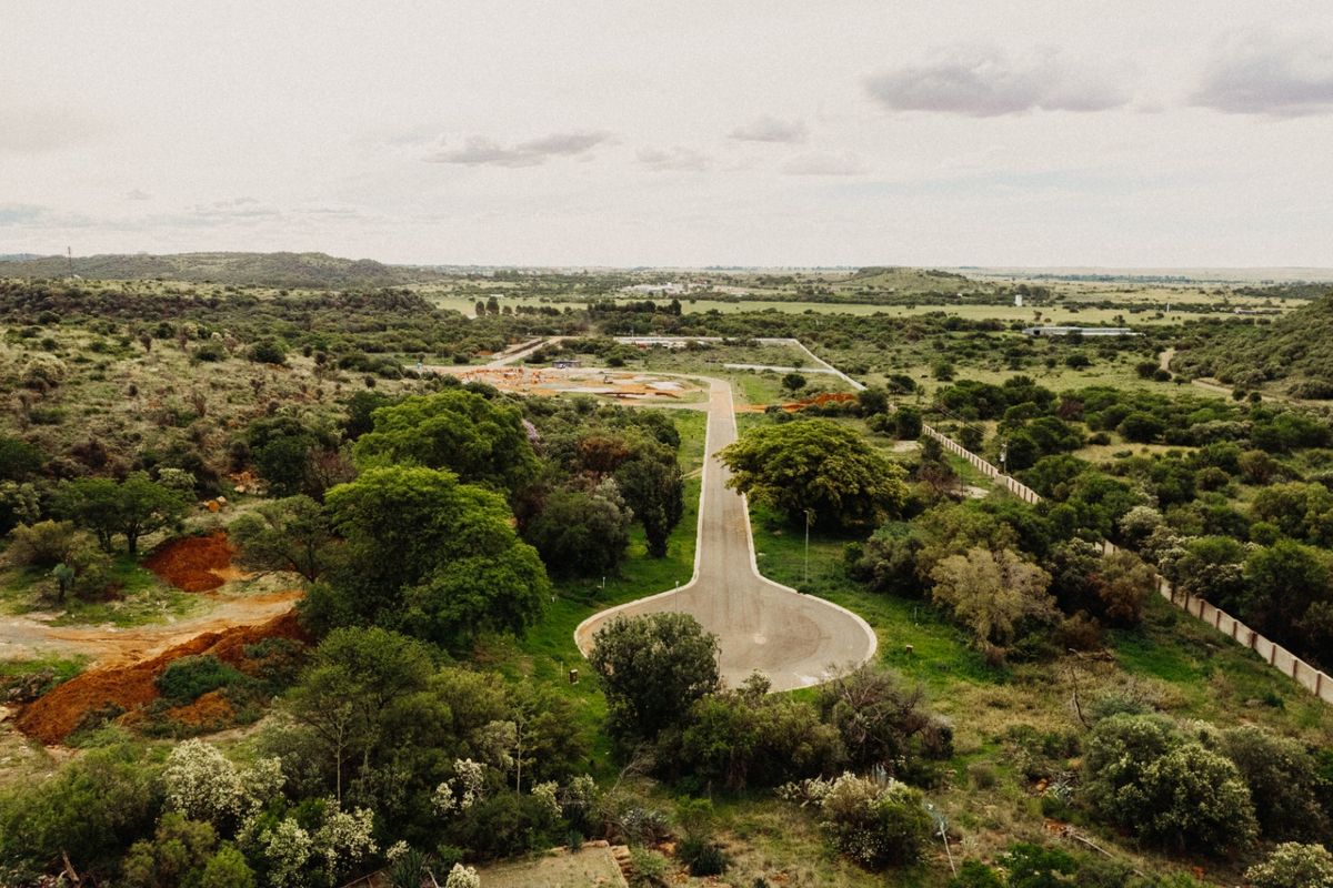 Aerial view of a residential development site featuring a paved cul-de-sac road surrounded by natural landscape and perimeter fencing.