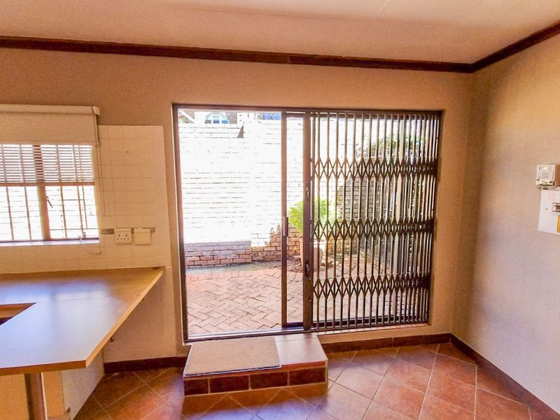 A functional kitchen area featuring tiled flooring, built-in countertops, and a sliding glass door providing direct access to a paved outdoor patio space.
