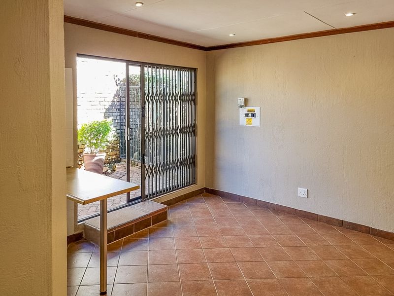 An empty living area featuring tiled floors, recessed lighting, and a sliding glass door with a security gate leading to an outdoor patio.