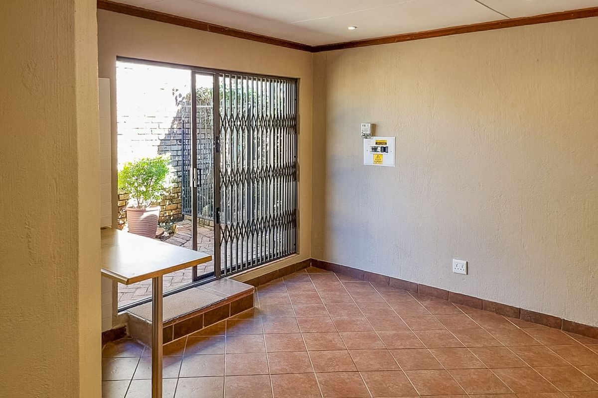 An empty living area featuring tiled floors, recessed lighting, and a sliding glass door with a security gate leading to an outdoor patio.