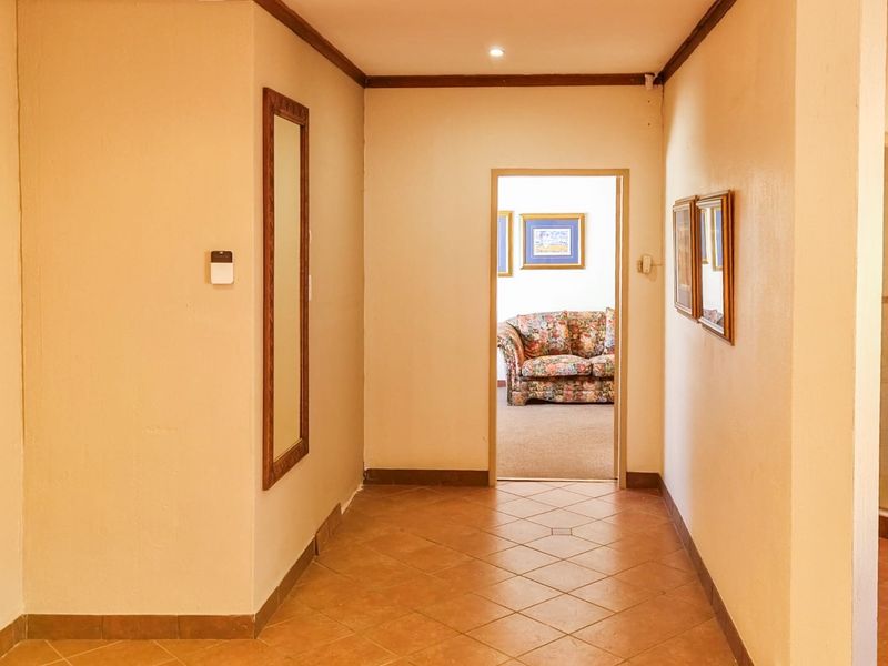 A clean, neutral hallway featuring tiled flooring and recessed lighting, providing a clear transition between living spaces.