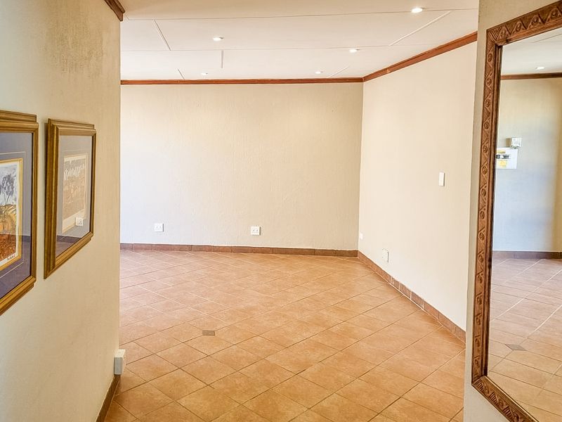 An empty, open-plan living area featuring neutral tiled flooring, recessed ceiling lighting, and clean wall finishes, ready for personalization.