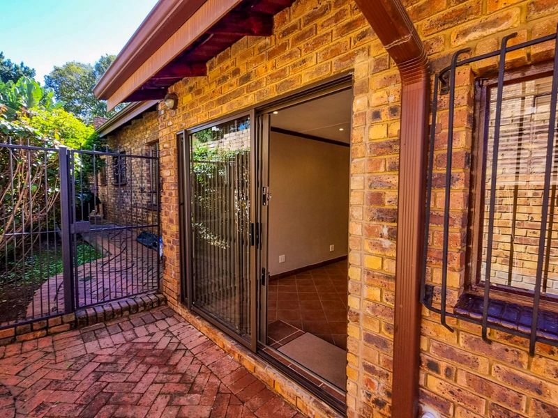 A paved patio area featuring face brick walls, a sliding glass door entrance, and security bars on the windows.