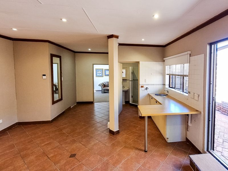 A functional scullery or utility area featuring tiled flooring, a built-in countertop with a sink, and direct access to an outdoor patio area.