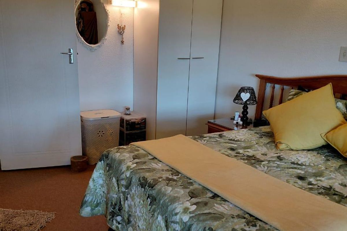 A functional bedroom featuring a built-in wardrobe, carpeted flooring, and wall-mounted lighting, offering a comfortable and practical living space.