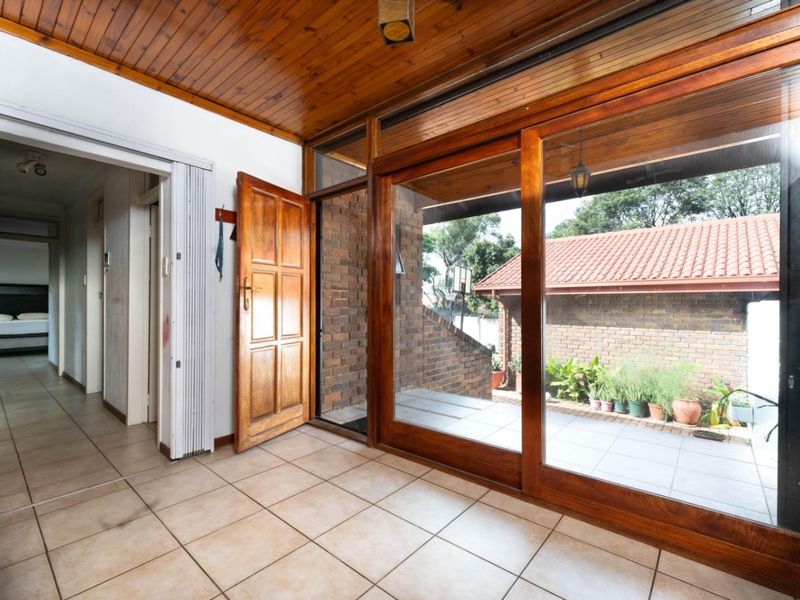 Entrance hall featuring timber ceiling, tiled flooring, and large sliding glass doors providing access to the outdoor patio area.