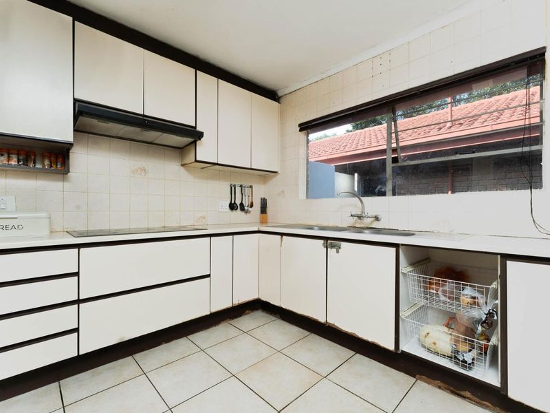 A dated kitchen featuring laminate cabinetry, a tiled backsplash, and ceramic flooring, offering significant potential for a modern renovation.
