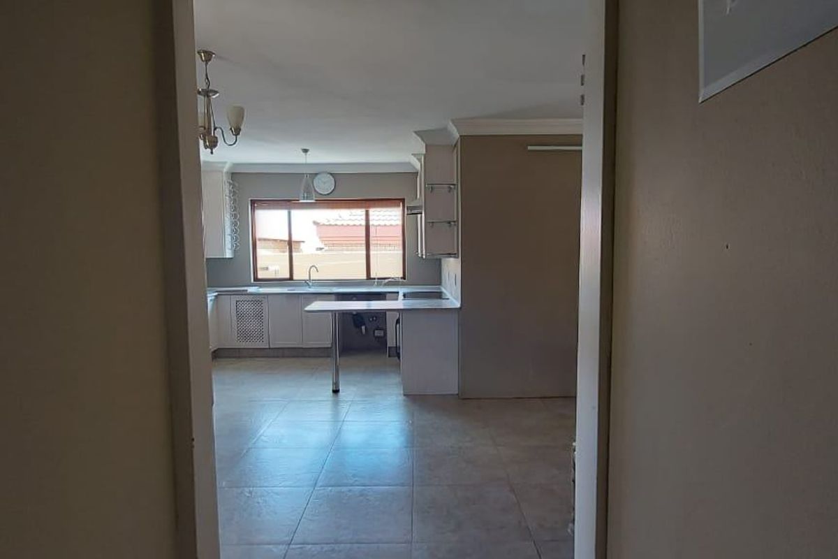 A view into an open-plan kitchen featuring tiled flooring, built-in cabinetry, and a central island, presented in a clean, vacant state.