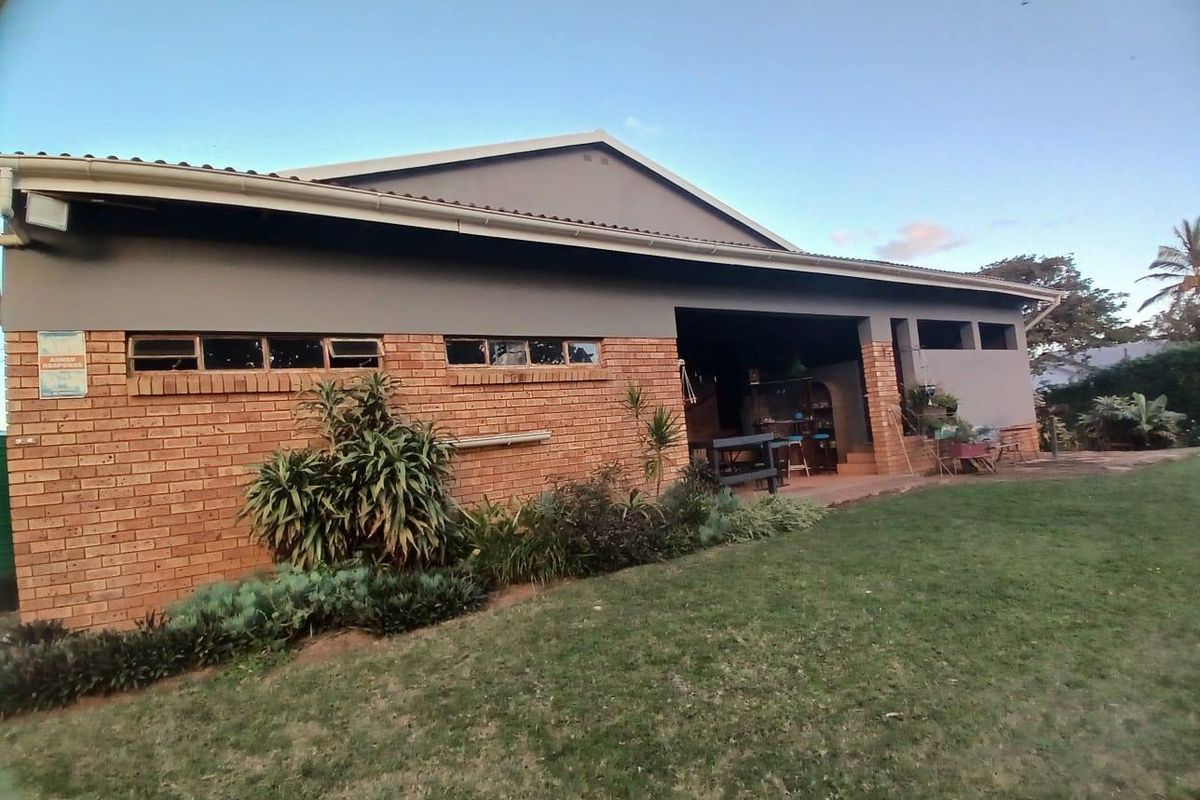 Rear view of the house featuring a brick and rendered facade with a covered patio area overlooking the garden.