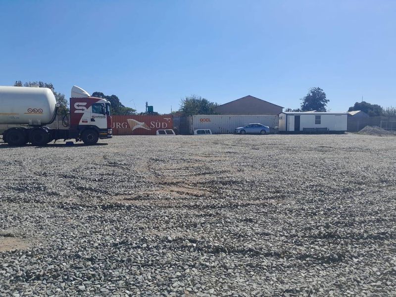 A large, open commercial yard featuring a gravel surface, suitable for industrial storage or parking.