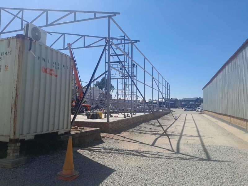 Commercial property under construction featuring a steel frame structure, concrete foundation, and brick plinth, currently in the development phase.