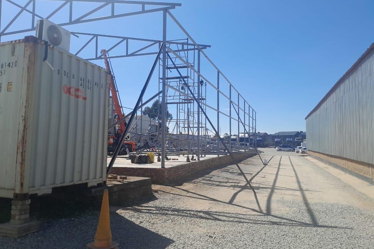 Commercial property under construction featuring a steel frame structure, concrete foundation, and brick plinth, currently in the development phase.