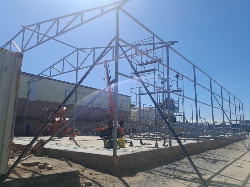 Construction site showing the steel frame structure and concrete foundation of a commercial building under development.