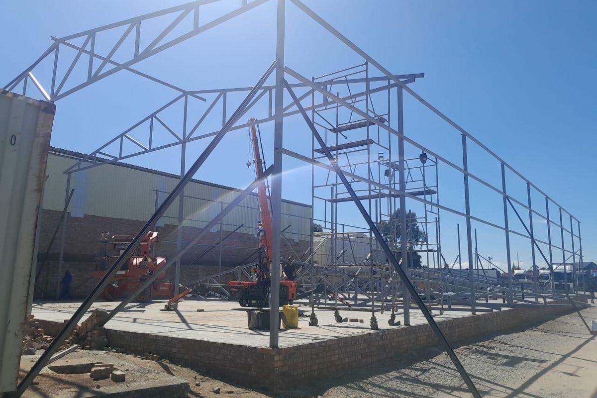 Construction site showing the steel frame structure and concrete foundation of a commercial building under development.
