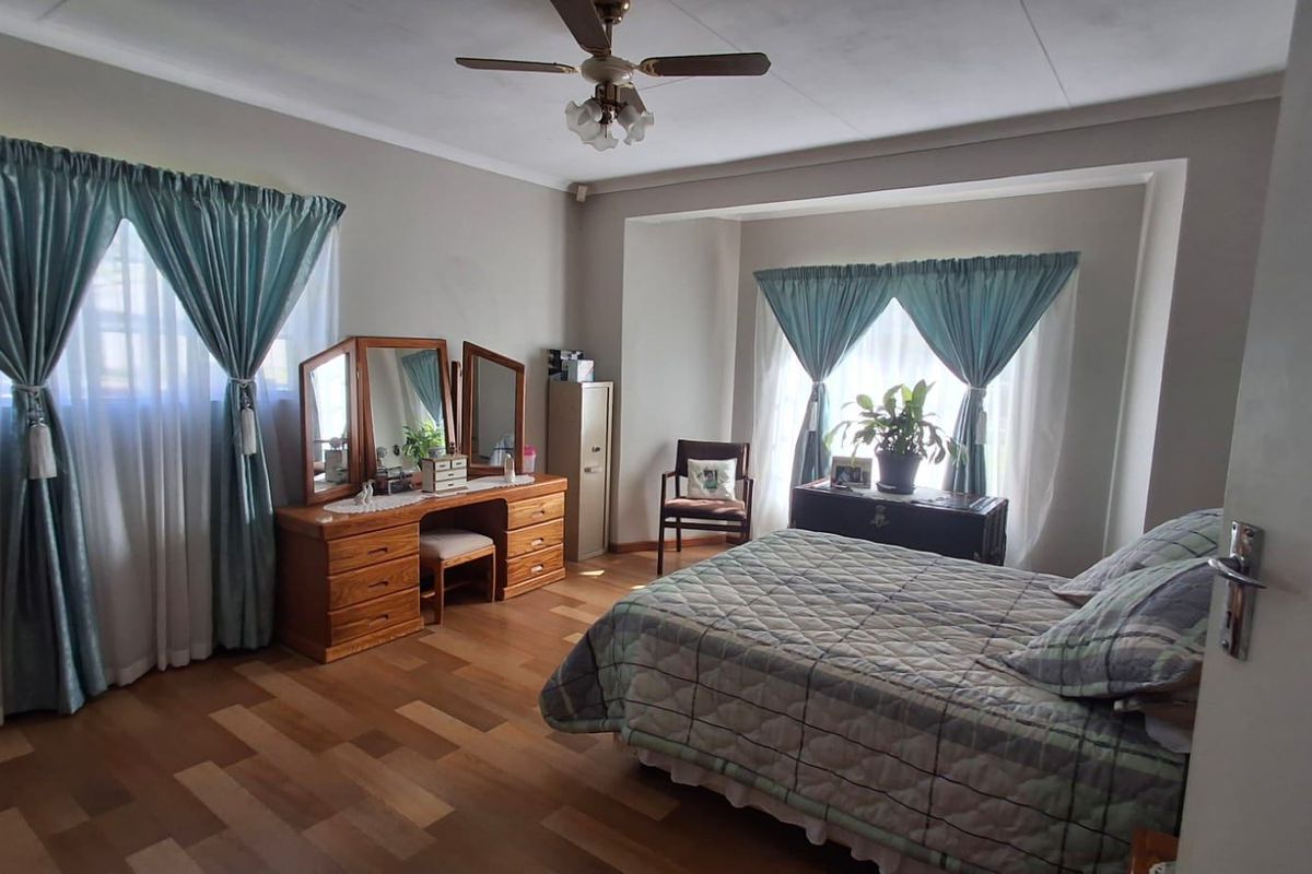Spacious bedroom featuring laminate flooring, a ceiling fan, and large windows with natural light.