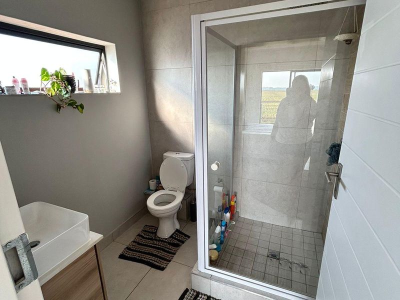 A modern bathroom featuring a glass-enclosed shower, a vanity with a basin, and neutral wall and floor tiling.