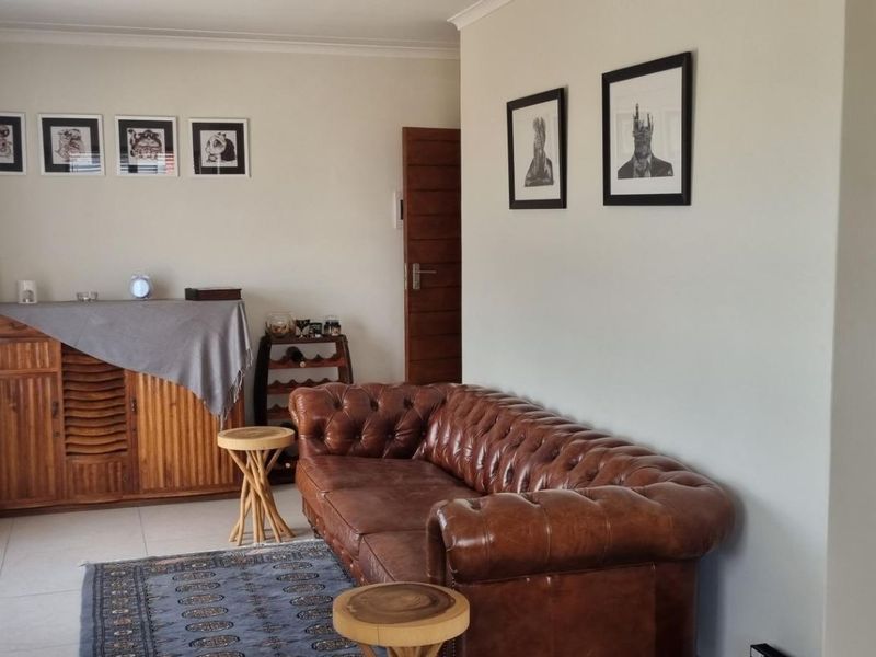 A well-maintained living room featuring neutral walls, tiled flooring, and classic cove cornicing, providing a comfortable and inviting space.