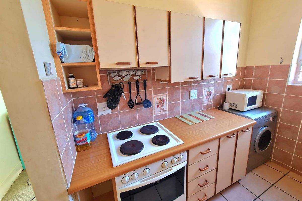A functional kitchen featuring built-in cabinetry, laminate countertops, an electric hob, and an integrated oven with tiled backsplash and flooring.