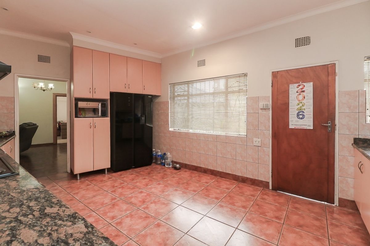 A functional kitchen featuring pink built-in cabinetry, granite countertops, tiled flooring, and a tiled backsplash, offering a practical layout with ample storage space.