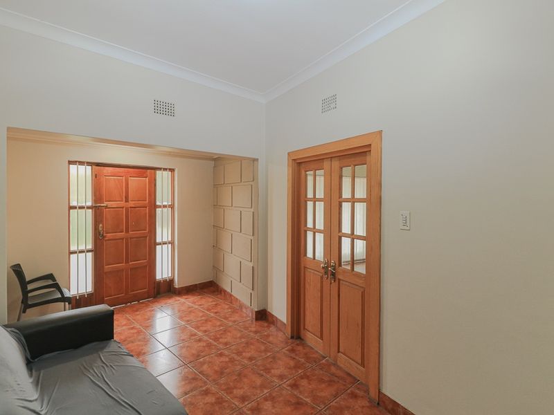 Entrance foyer featuring terracotta floor tiles, timber double doors, and a solid timber front door with side light panels.