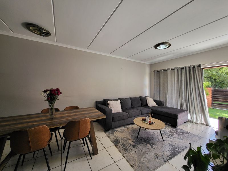 Open-plan living and dining area featuring tiled flooring, recessed ceiling lighting, and direct access to an outdoor patio through a sliding glass door.