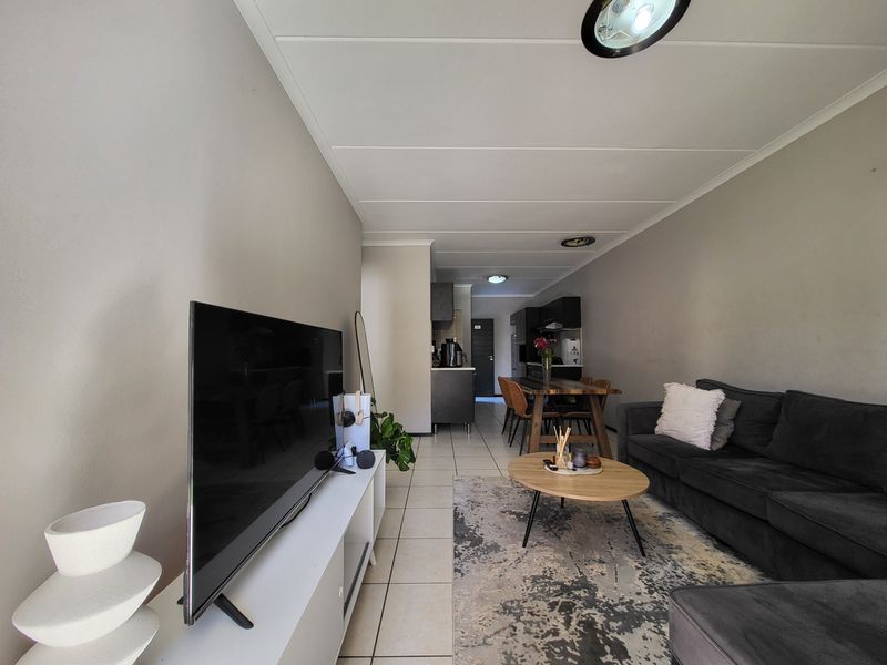 An open-plan living and dining area featuring tiled flooring and a connected kitchen space, providing a functional layout for modern apartment living.