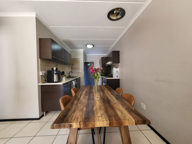 Open plan kitchen and dining area featuring dark wood cabinetry, tiled flooring, and integrated appliances in a functional layout.