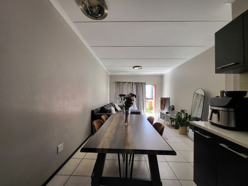 Open-plan living and dining area featuring tiled flooring, ceiling panels, and direct access to an outdoor space through a sliding door.