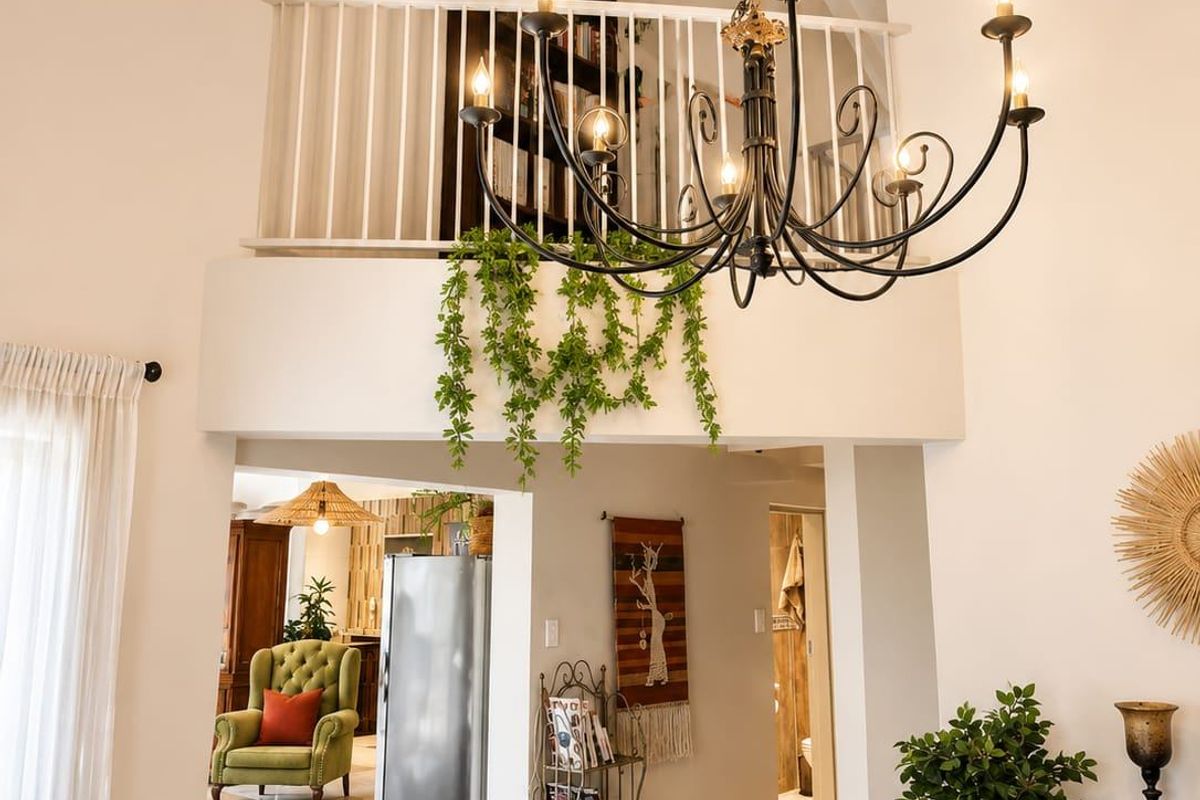 Spacious living area featuring a double-volume vaulted ceiling with exposed beams, a decorative chandelier, and a mezzanine level overlooking the main floor.