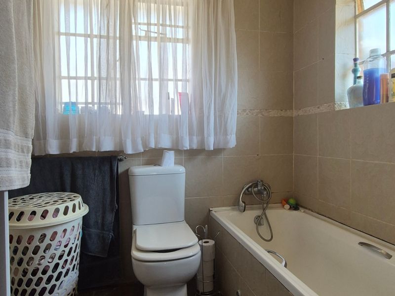 A functional bathroom featuring a standard bathtub, toilet, and tiled wall finishes, offering potential for modernization and cosmetic updates.