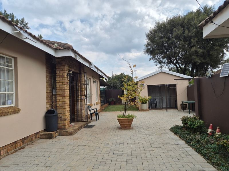 A paved rear courtyard area featuring brick exterior walls, a tiled roof, and a detached outbuilding, providing a functional outdoor space.
